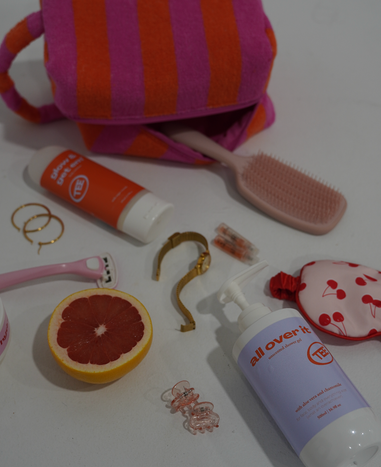 Assorted items including a toothbrush, bottle, and fruit on a white surface with a striped towel.
